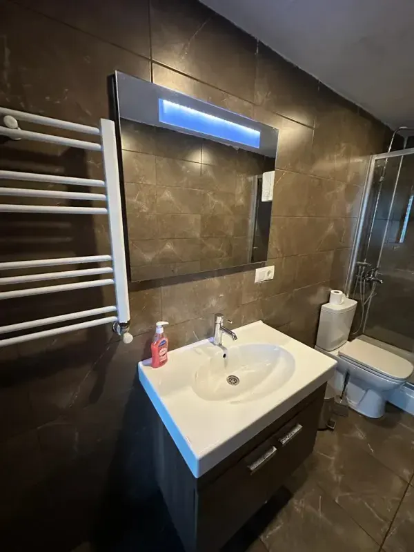 Modern bathroom with sink, under-sink cabinet, and illuminated mirror
